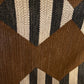 Textile sample with geometric pattern held by a hand on a wooden surface