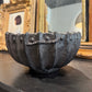 Decorative black shell-shaped bowl on a dark surface with gold-framed mirrors in the background.