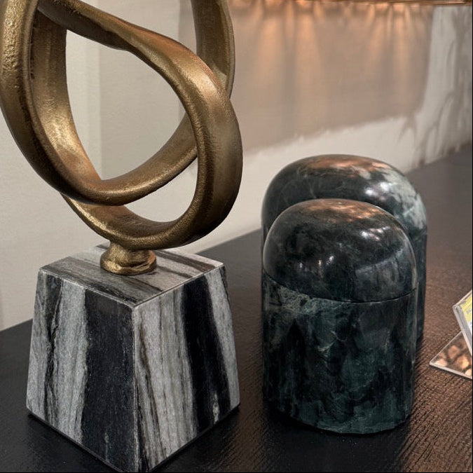 Decorative bronze sculpture on a marble base with a wall mirror in the background