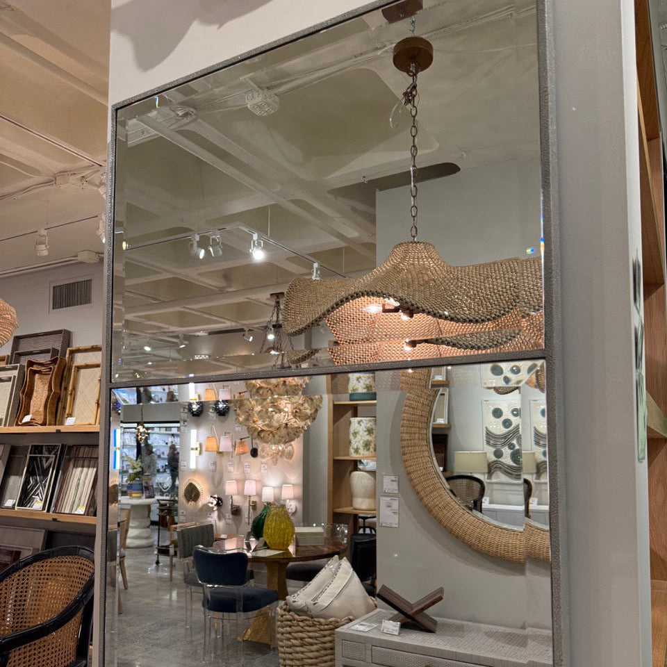 Large mirror reflecting interior decor with furniture and lighting fixtures.