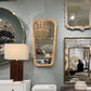 Decorative mirrors and lamps on a gray wall with furniture below.