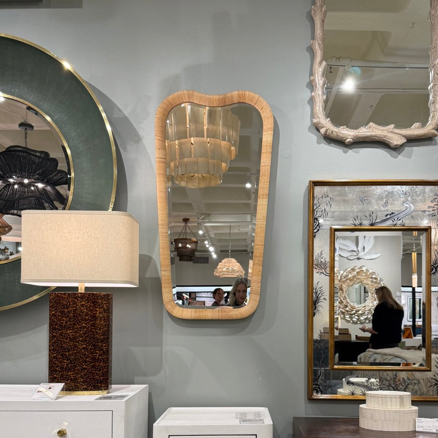 Decorative mirrors and lamps on a gray wall with furniture below.