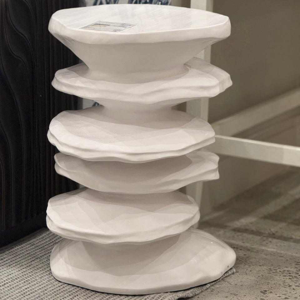 White, modern side table with a textured surface on a carpeted floor.