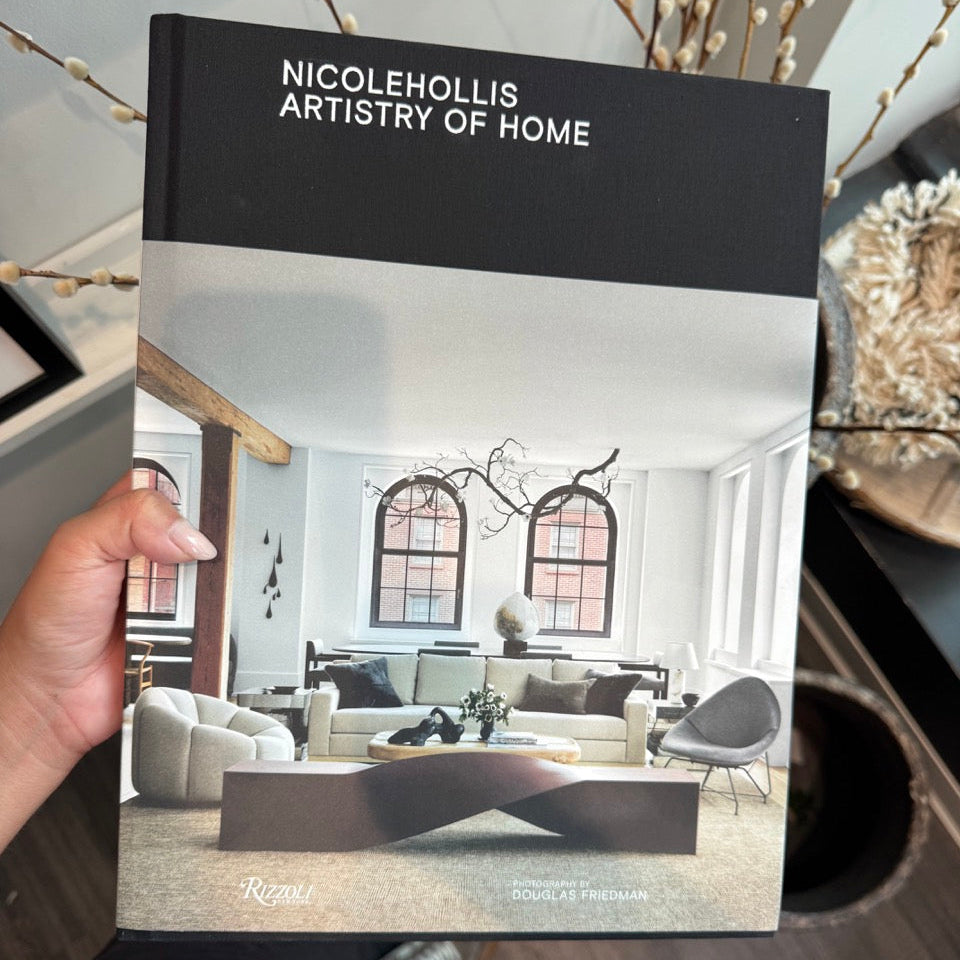 Book titled 'NicoleHollis Artistry of Home' held by a person, with a living room scene on the cover.