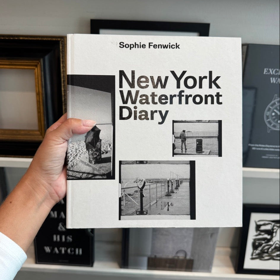 Book titled 'New York Waterfront Diary' by Sophie Fenwick held in front of a bookshelf.