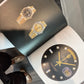 Two gold watches on an open book with a close-up of a watch face.