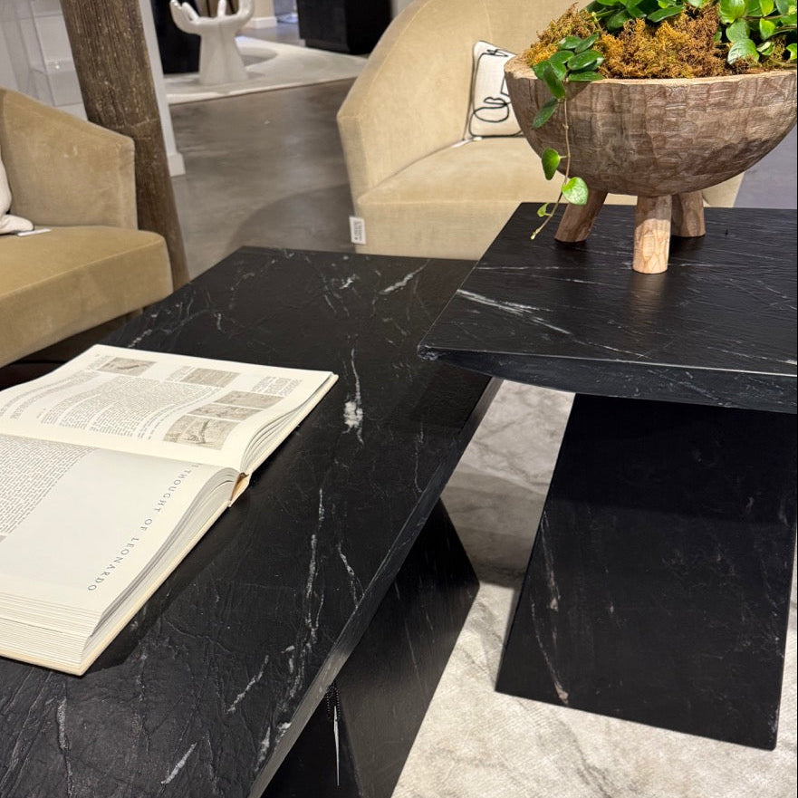 Black marble coffee table with a book and plant in a modern living room setting