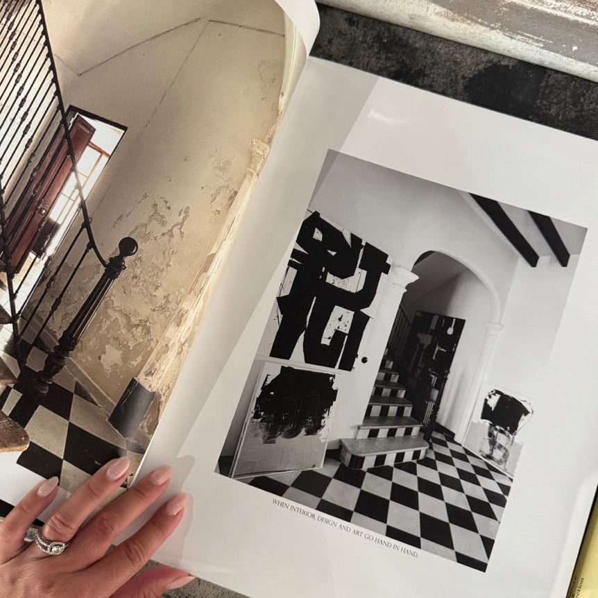 Person holding a framed black and white print of a room with a checkered floor.