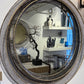 Round decorative mirror with a black wireframe design on a white wall.