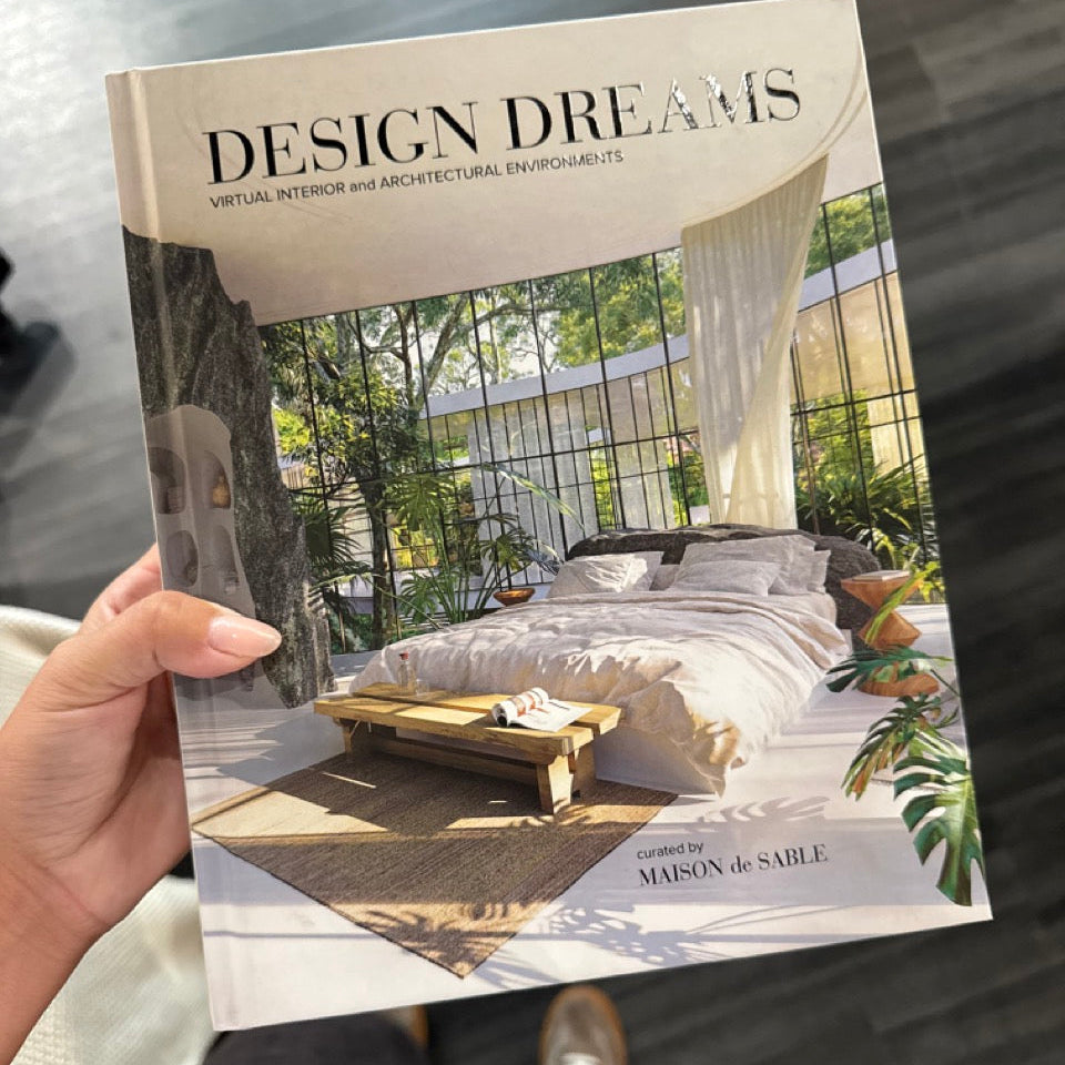 Book titled 'Design Dreams' held by a person with a blurred background