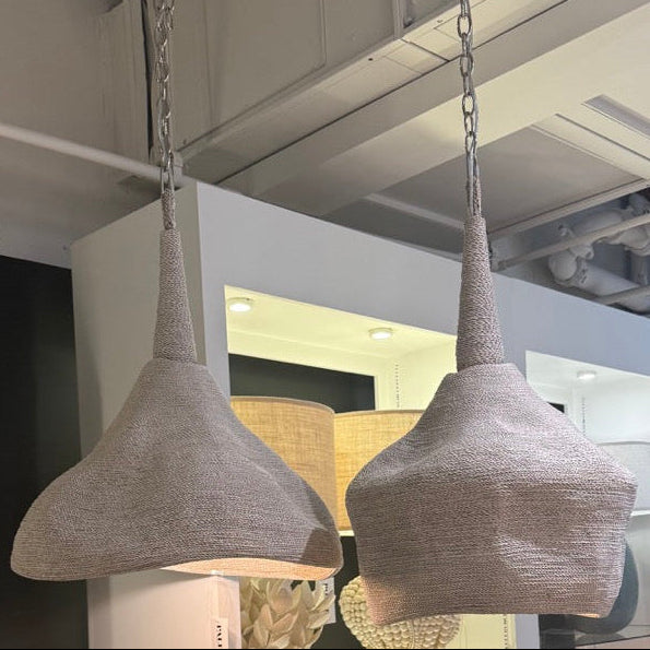 Two hanging pendant lights with textured shades in a showroom setting.
