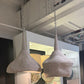 Two concrete pendant lights hanging in a showroom setting.