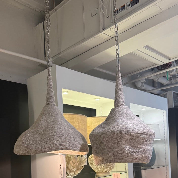 Two concrete pendant lights hanging in a showroom setting.