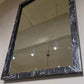 Rectangular mirror with a black marble-like frame on a wall.