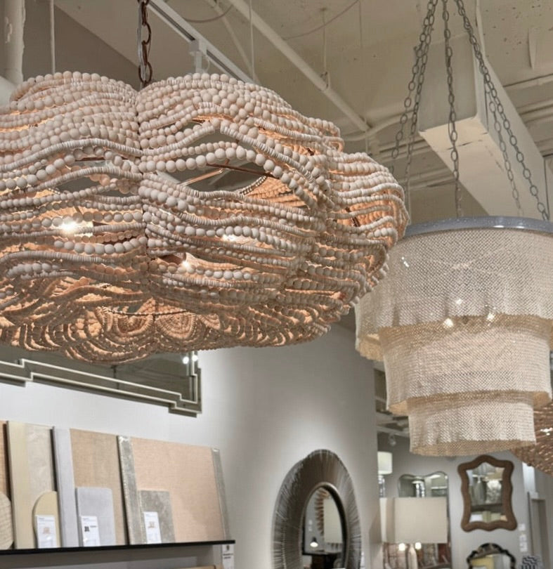 Large beaded chandelier hanging in a room with decor samples and mirrors.