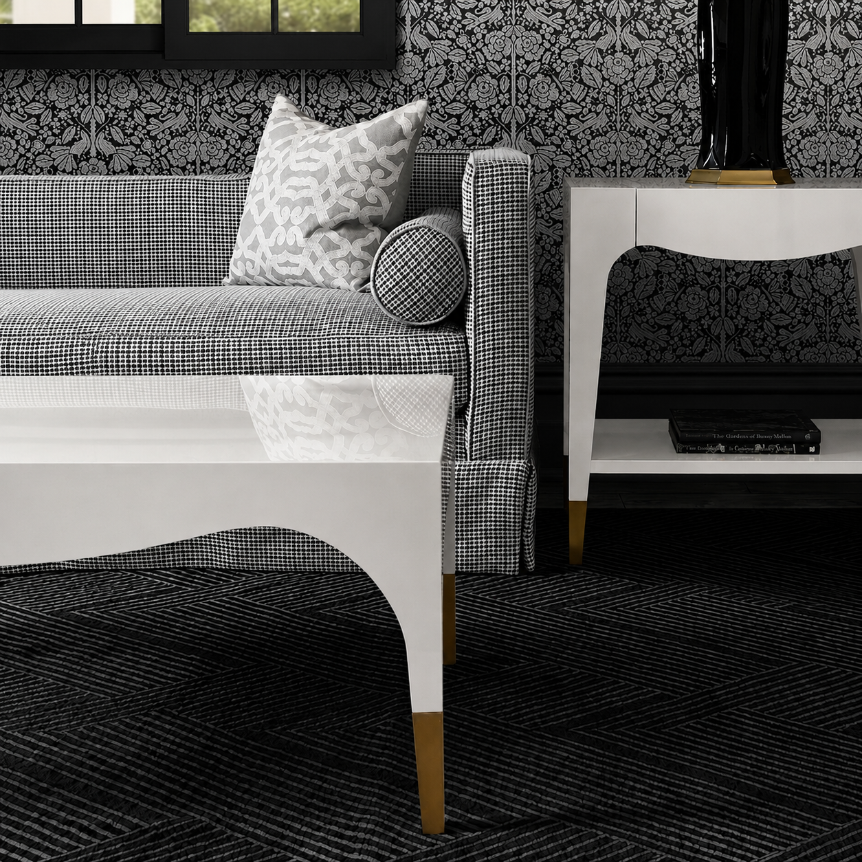 Living room with patterned sofa, coffee table, and decorative pillows against a black and white floral wallpaper.