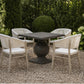 A 4-piece outdoor dining set featuring a square pedestal table and four matching armchairs with distressed off-white frames and white seats, set on a gravel patio in a garden.