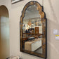 Large decorative mirror with a reflective surface showing a room interior.