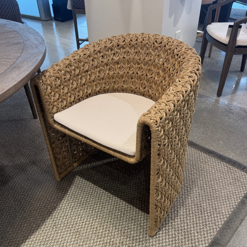 Woven chair with a white cushion on a textured floor