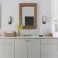 A modern bathroom vanity setup featuring a light gray double-sink cabinet with a white countertop, a large rectangular wicker mirror, blue and white patterned floor tiles, and matching wicker decorative baskets.
