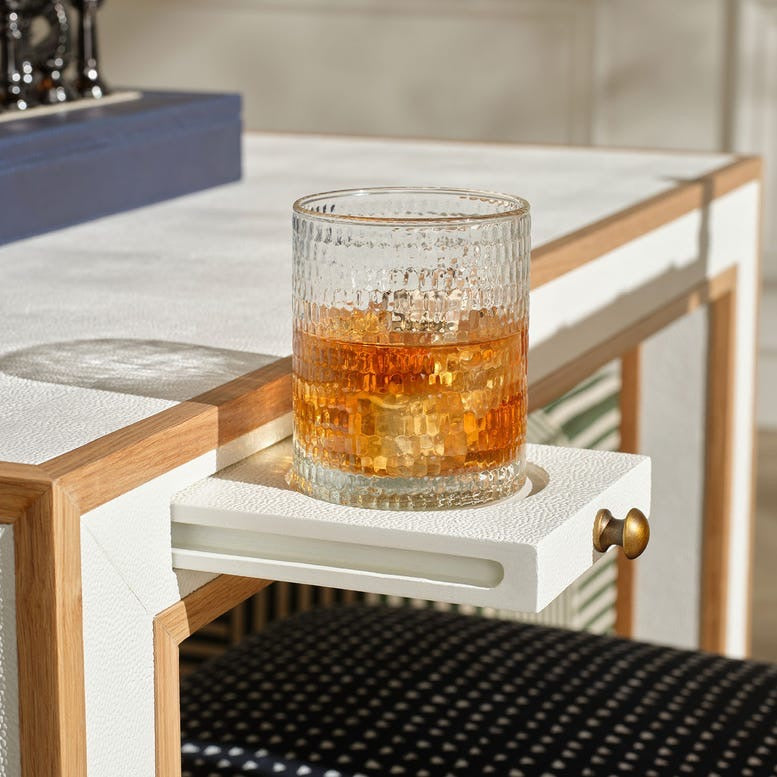 Glass of amber liquid on a white tray with wooden frame