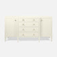 An off-white mid-century modern sideboard with two cabinet doors, four drawers, and small gold knobs, set against a light gray background.