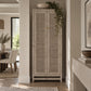 A tall two-door cabinet with woven cane or rattan panels and small gold knobs, shown in a real interior hallway with a dining area on the left and a console table on the right.