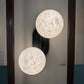 Two spherical wall lights with intricate designs on a dark background