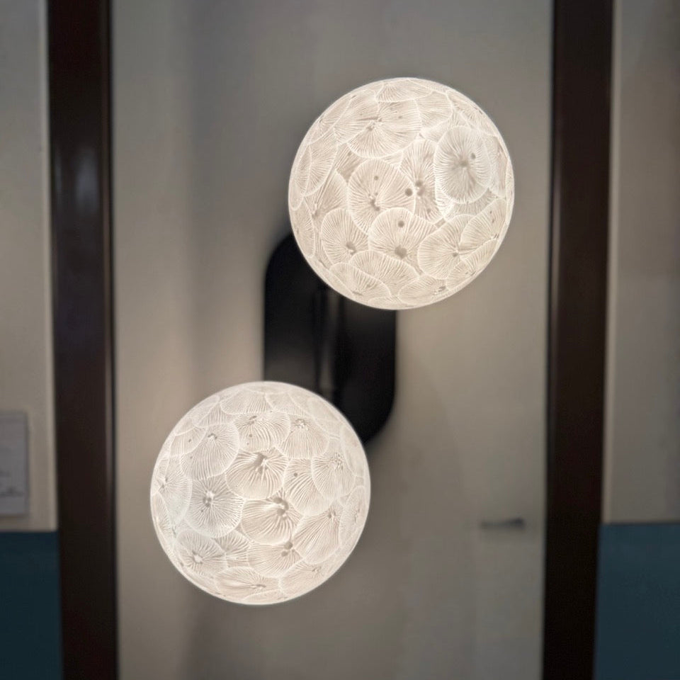 Two spherical wall lights with intricate designs on a dark background