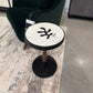 Black chair with a round table featuring a unique design on a textured floor.