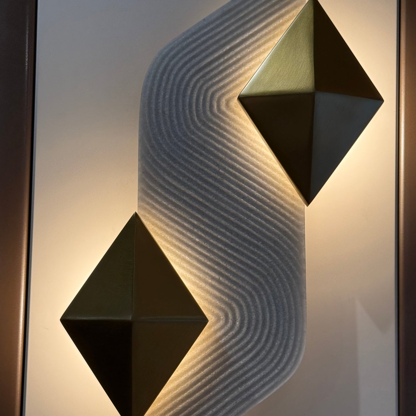 Modern wall sconce with geometric design on a textured wall