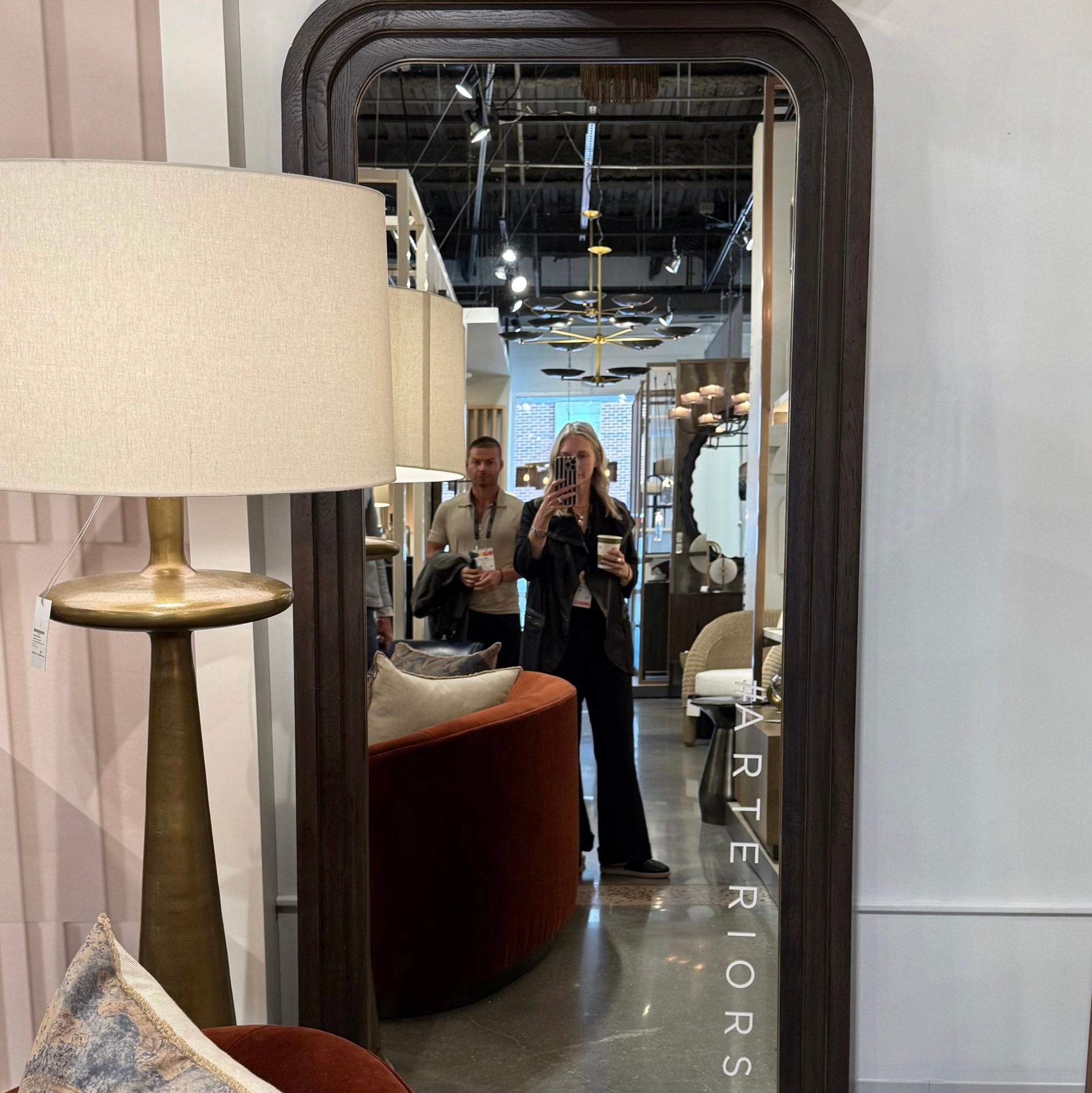 Large floor mirror with a person taking a photo, surrounded by interior decor elements.