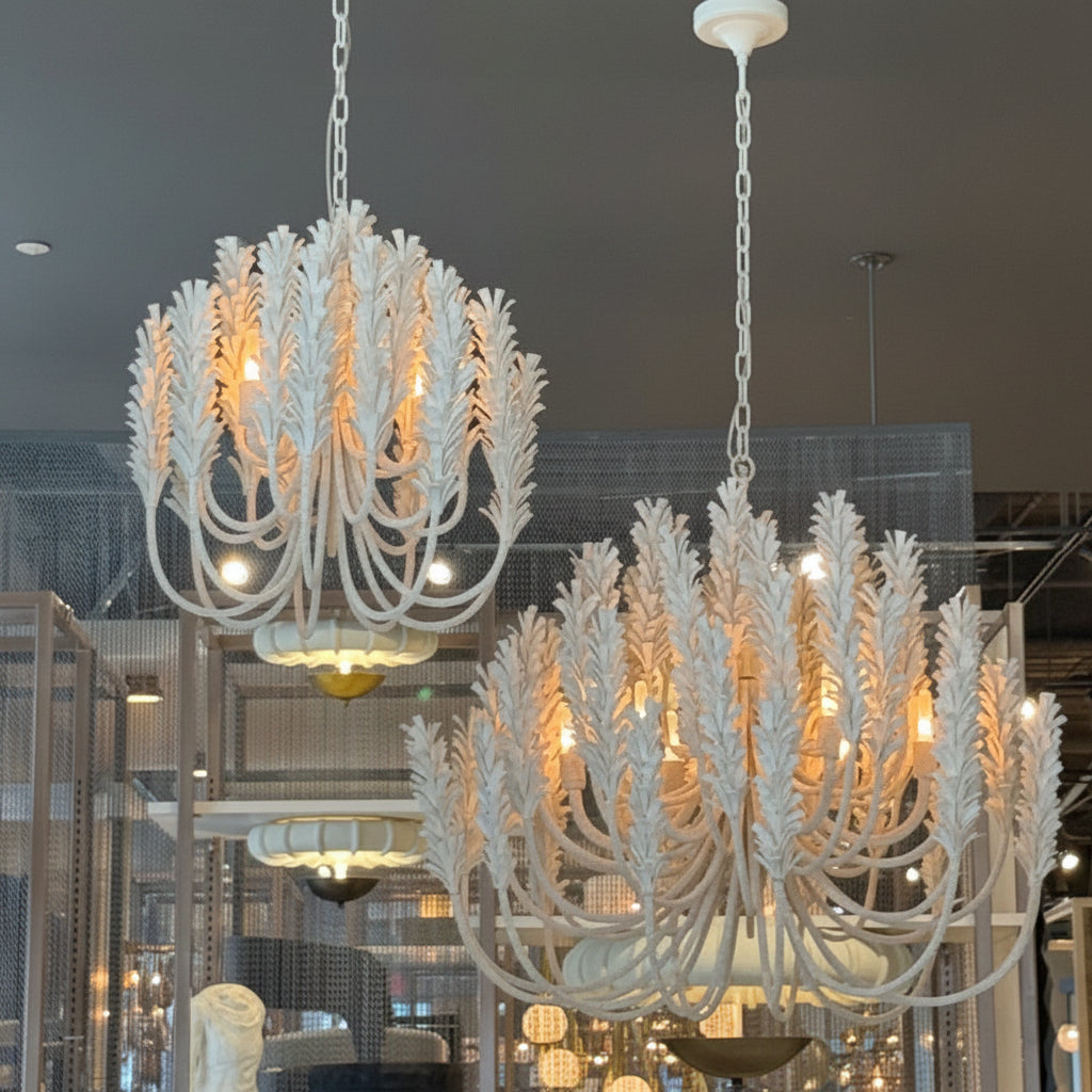Two ornate chandeliers hanging in a showroom with reflective floor and ceiling.