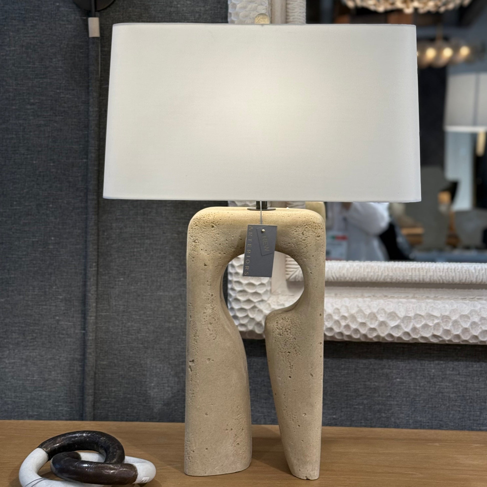 Table lamp with a beige base and white shade in a room setting.