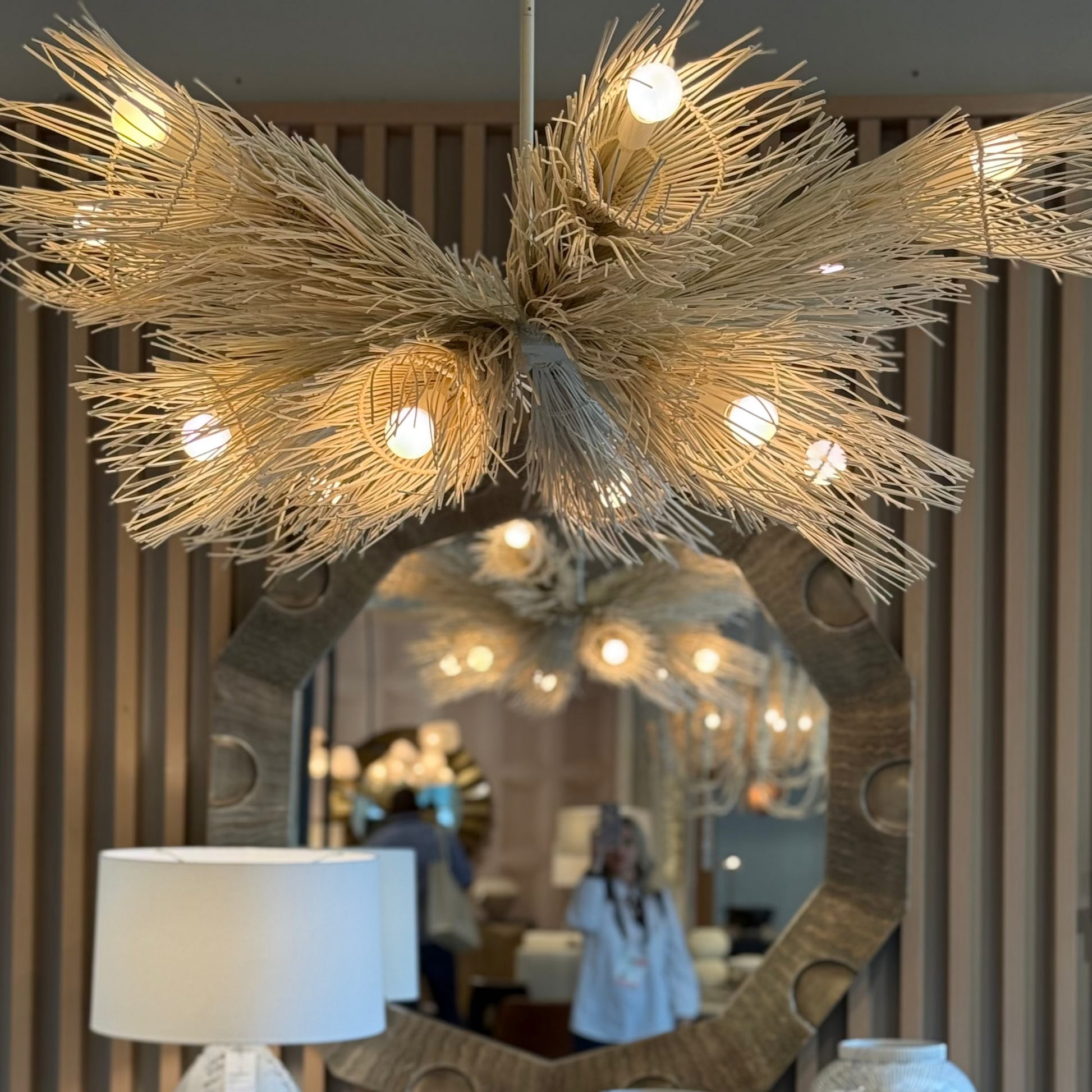 Decorative chandelier with lights above a mirror and lamps.