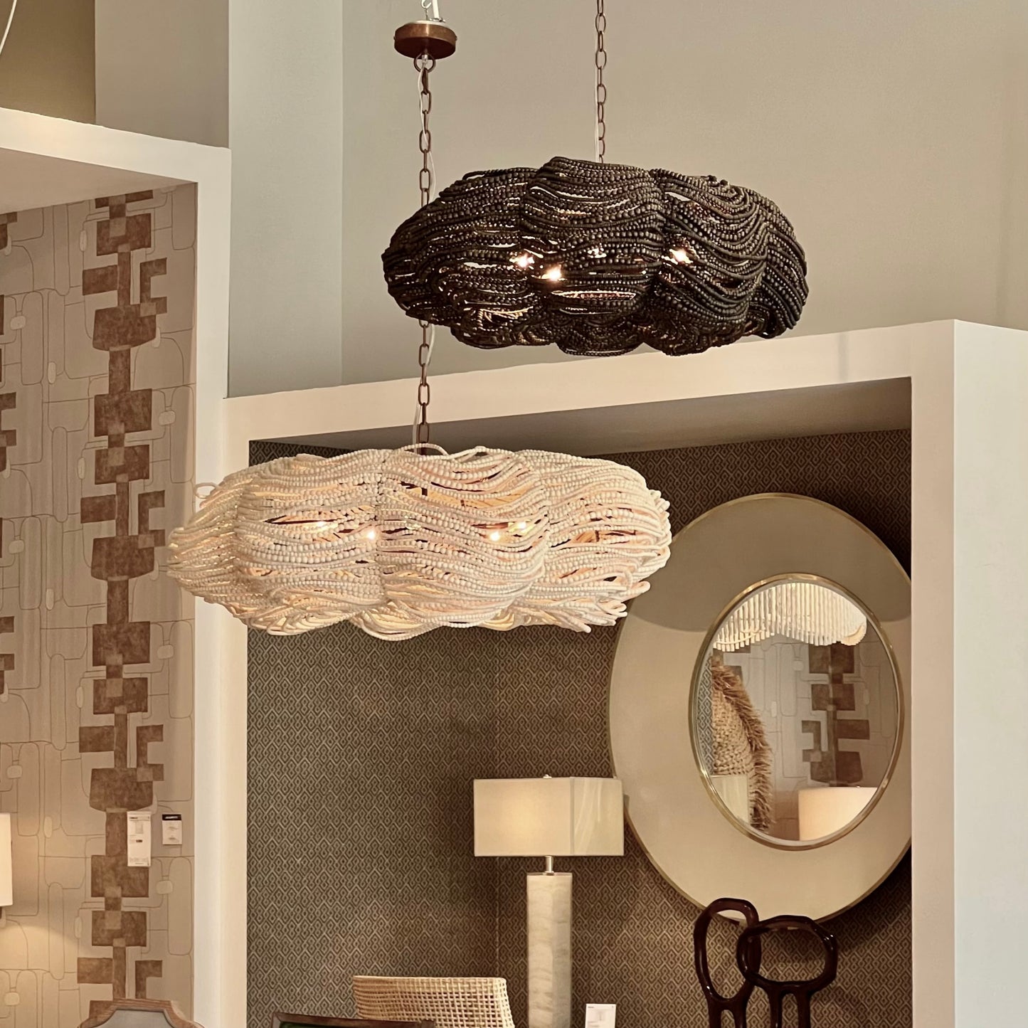 Two decorative chandeliers hanging in a room with a mirror and lamp.