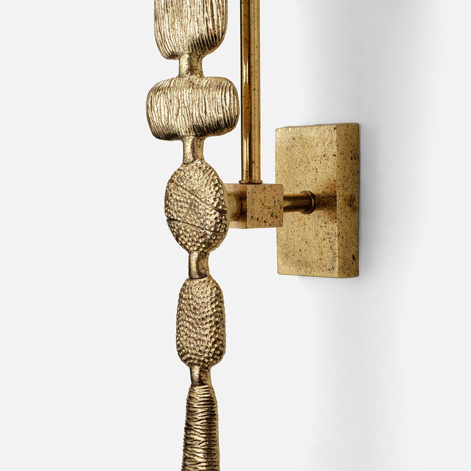 Decorative wall sconce with textured gold base and white shade on a light gray background