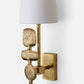 Decorative wall sconce with textured gold base and white shade on a light gray background
