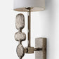 Decorative wall sconce with textured metal design and white lampshade on a light gray background