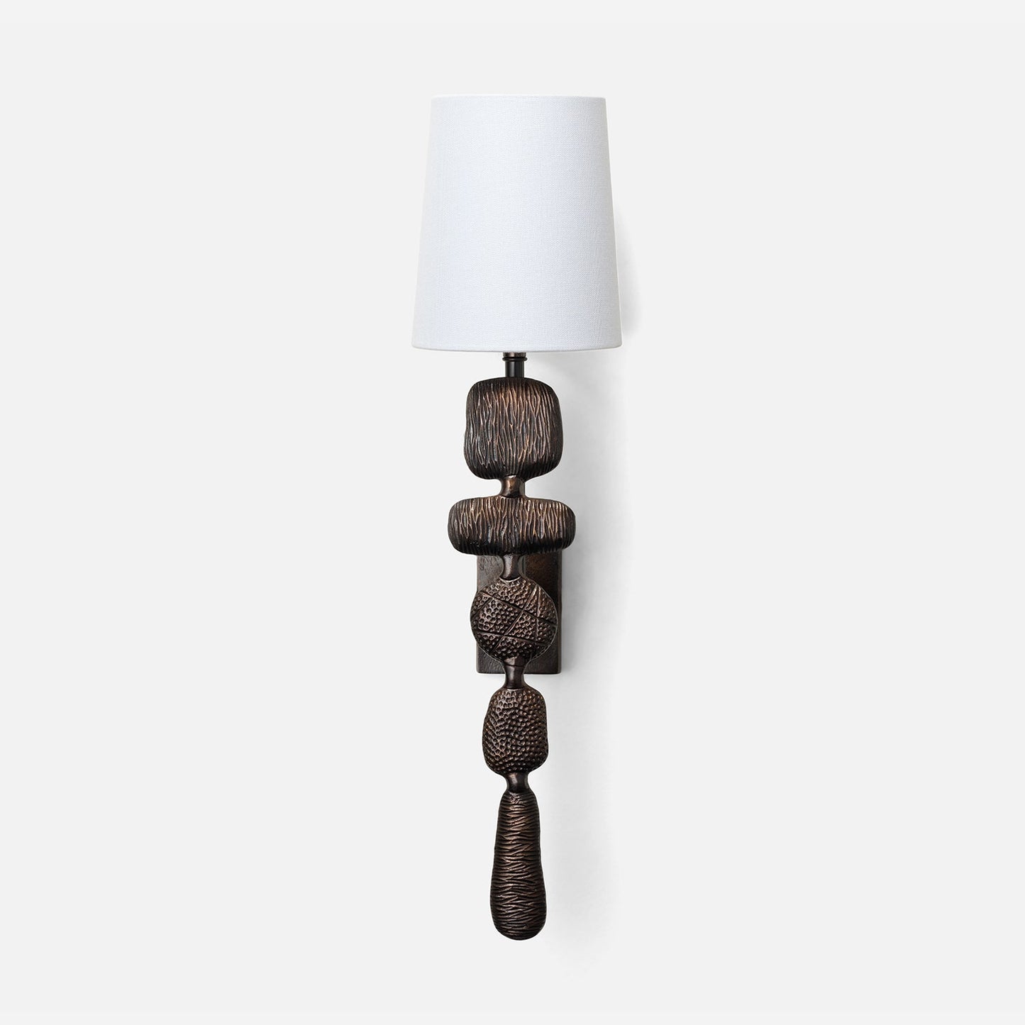 Decorative wall lamp with a textured base and white shade on a white background