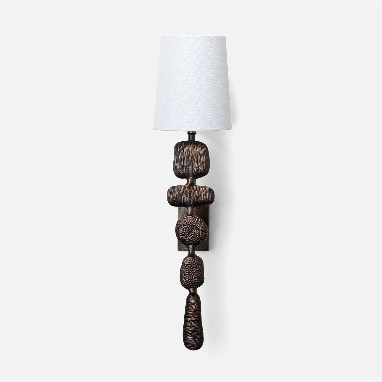 Decorative wall lamp with a textured base and white shade on a white background
