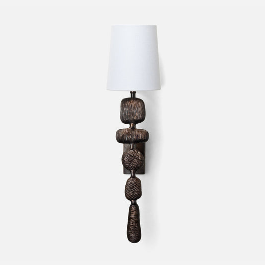 Decorative wall lamp with a textured base and white shade on a white background