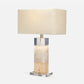 Table lamp with a rectangular crystal base and beige fabric shade on a white background