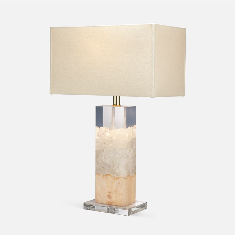 Table lamp with a rectangular crystal base and beige fabric shade on a white background