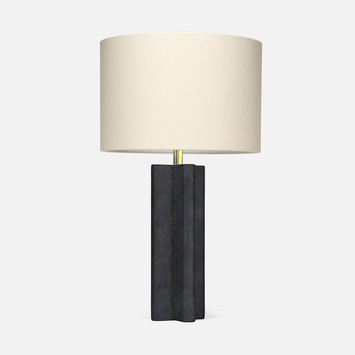 A modern table lamp with a dark charcoal gray sculptural base and a cylindrical off-white fabric drum shade, set against a plain light gray background.
