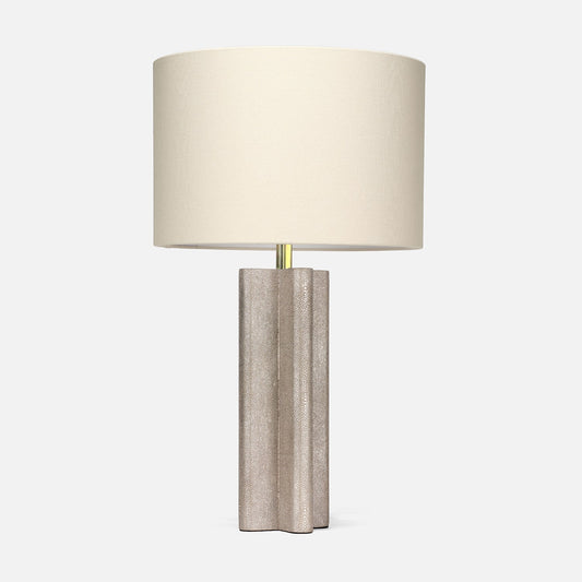 Textured neutral table lamp with a sculptural fluted base, brass accent, and large ivory drum shade on a white background.