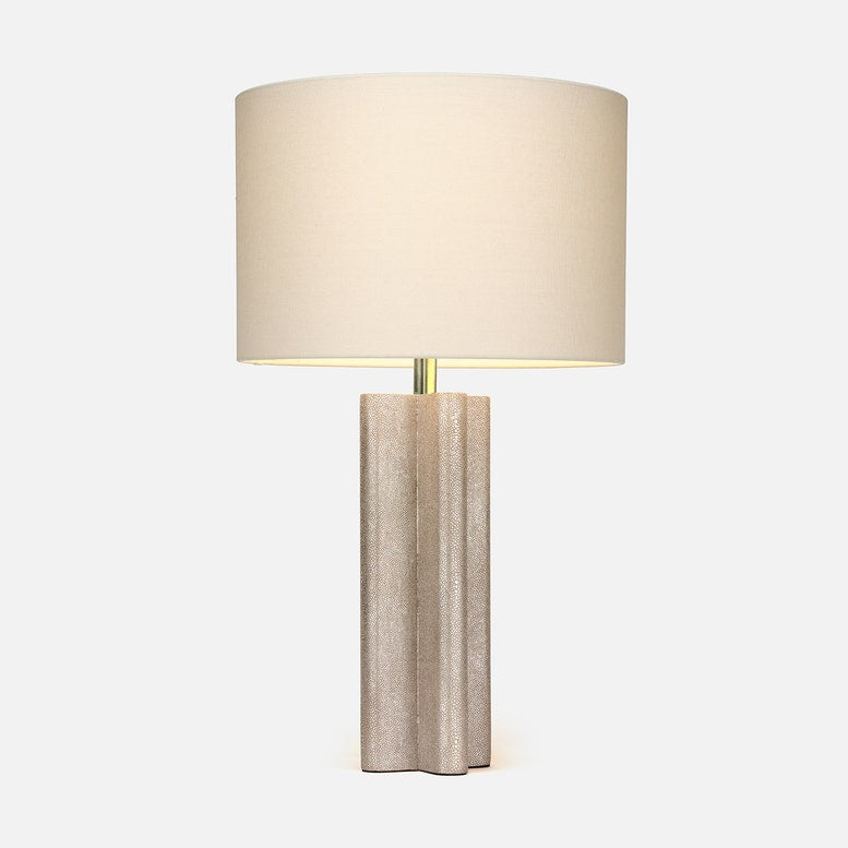 Textured neutral table lamp with a sculptural fluted base, brass accent, and large ivory drum shade on a white background.