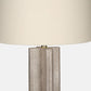 Textured neutral table lamp with a sculptural fluted base, brass accent, and large ivory drum shade on a white background.