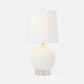 A table lamp with a textured white spherical base, a clear acrylic pedestal foot, and a white fabric drum shade with a small white finial on top, photographed against a clean white background.