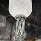 Close-up of a white jellyfish-shaped lamp with a textured surface against a dark background.